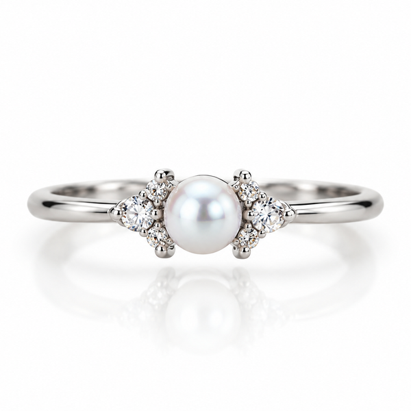 Silberfarbener Kiara Ring mit schmaler Ringschiene, weißer Perle und jeweils drei klaren Schmucksteinen auf beiden Seiten.